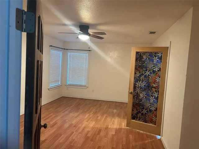 a view of an empty room with wooden floor and a window
