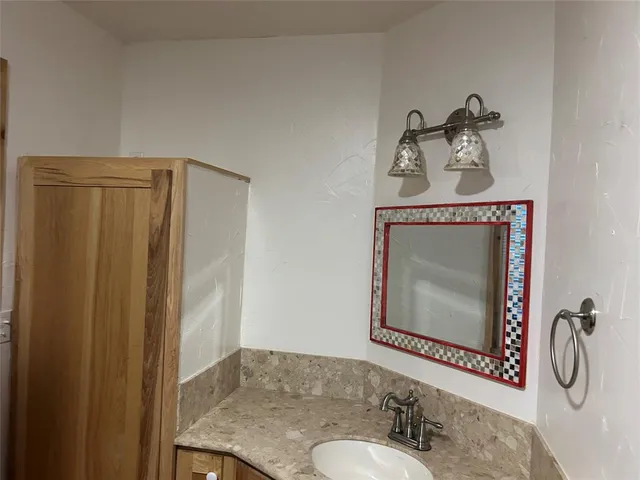 a bathroom with a granite countertop sink with a mirror