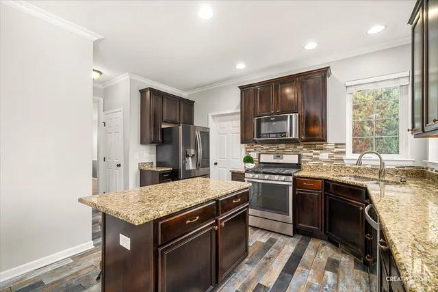 a kitchen with granite countertop a sink stove and refrigerator