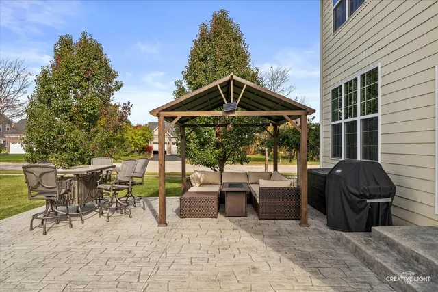a view of a patio with table and chairs under an umbrella with large trees