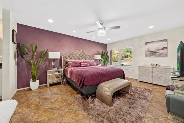 a spacious bedroom with a bed and a flat screen tv