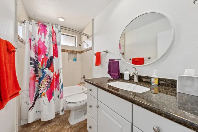 a bathroom with a granite countertop sink mirror vanity and toilet