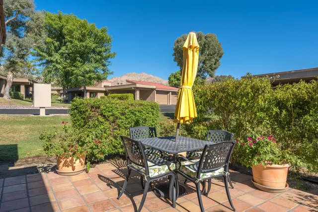 a patio with table and chairs and potted plants