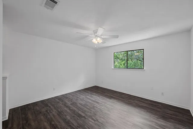 an empty room with wooden floor and ceiling fan
