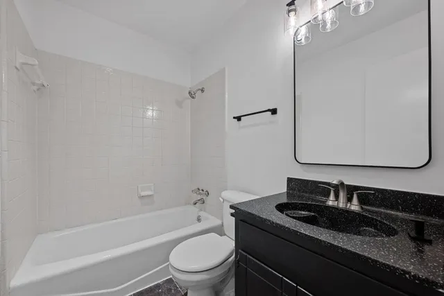 a bathroom with a granite countertop sink toilet mirror and bathtub