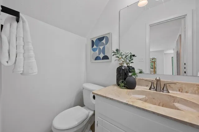 a bathroom with a granite countertop toilet sink and mirror