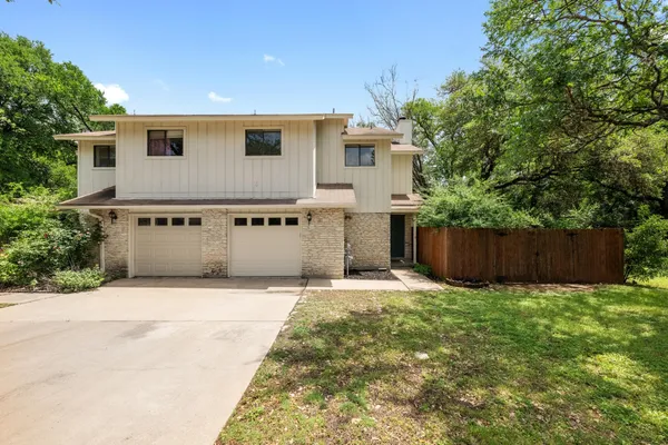 a front view of house with yard and trees in the background