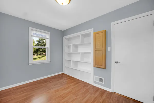 a view of an empty room with a window and wooden floor