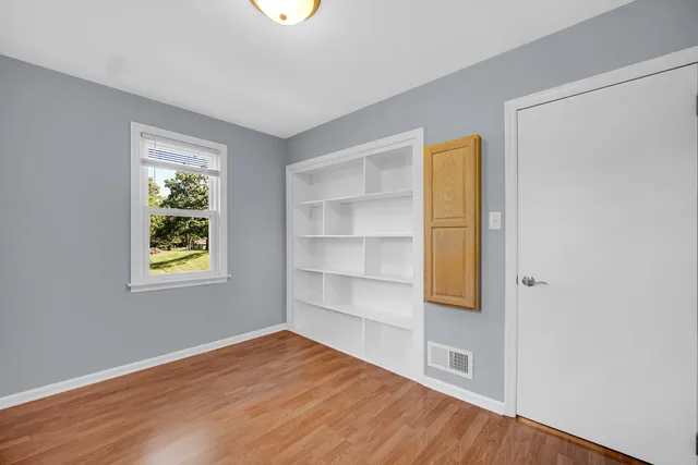 a view of an empty room with a window and wooden floor
