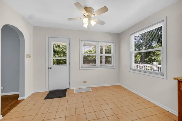 a view of an empty room with window and chandelier fan