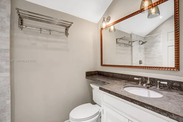 a bathroom with a granite countertop sink mirror vanity and toilet