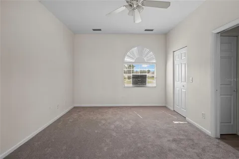an empty room with windows and ceiling fan