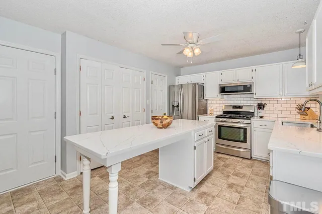 a kitchen with stainless steel appliances kitchen island granite countertop a stove a sink and a refrigerator