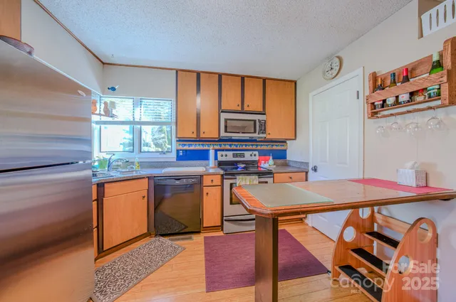 a kitchen with stainless steel appliances granite countertop a stove a sink dishwasher and a refrigerator with wooden cabinets