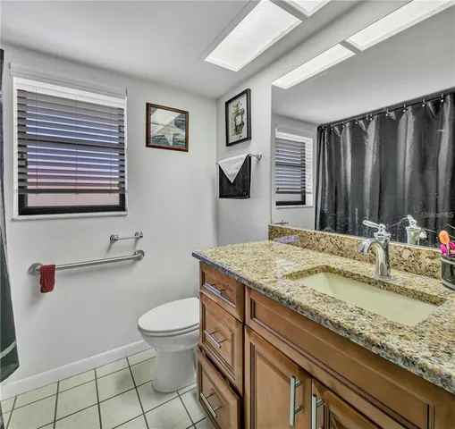 a bathroom with a granite countertop sink a toilet and mirror