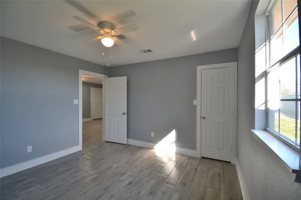 a view of an empty room with wooden floor and a window