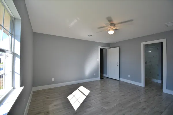 an empty room with wooden floor and windows