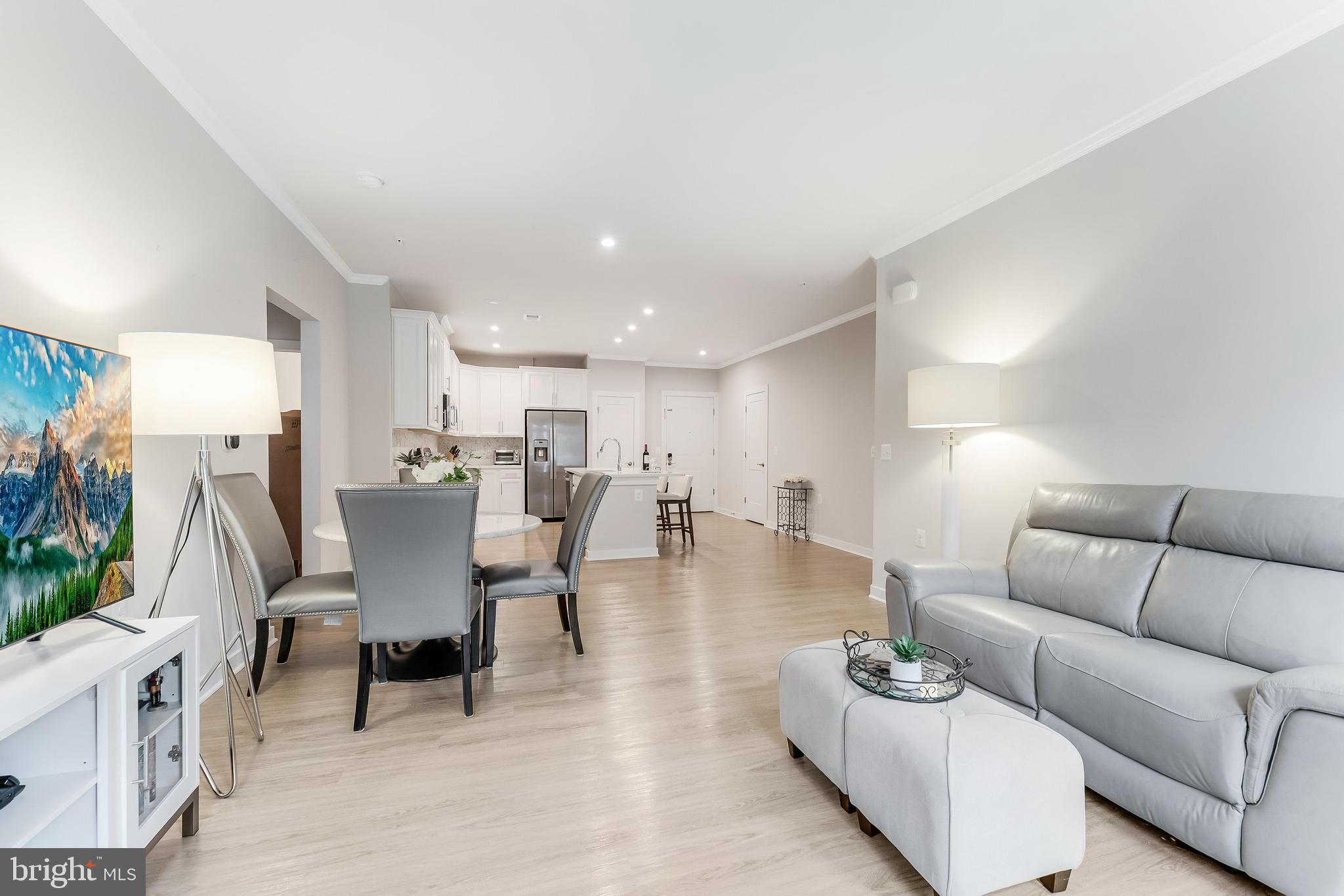 1675 Bandit Loop, Unit 105B Reston, VA 20190 - Photo 2 of 27 a living room with furniture and a dining table with wooden floor