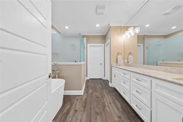 a spacious bathroom with a granite countertop sink a toilet a large mirror a vanity and shower
