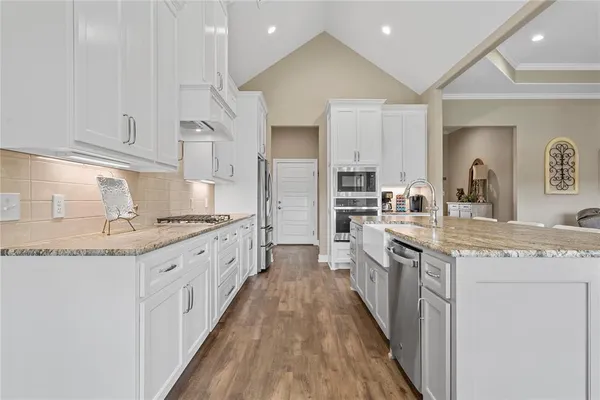 a large kitchen with stainless steel appliances granite countertop a lot of counter space and wooden floors