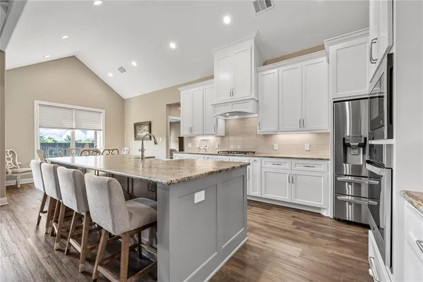 a kitchen with kitchen island granite countertop a sink stove and refrigerator