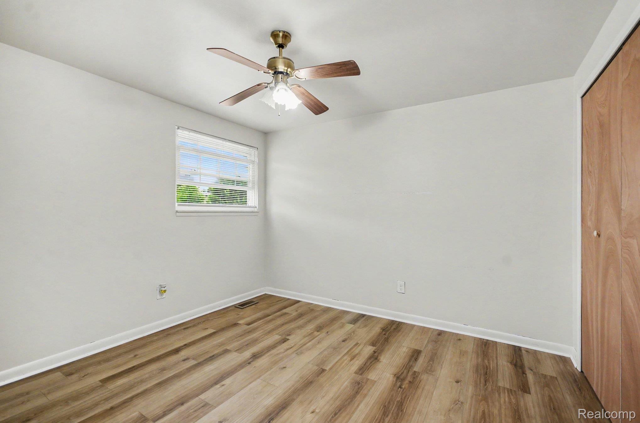 6653 Flintlock Ridge Utica, MI 48317 - Photo 19 of 31 Room featuring wood-finish flooring, white baseboards, a ceiling fan with light fixture, and a window with blinds