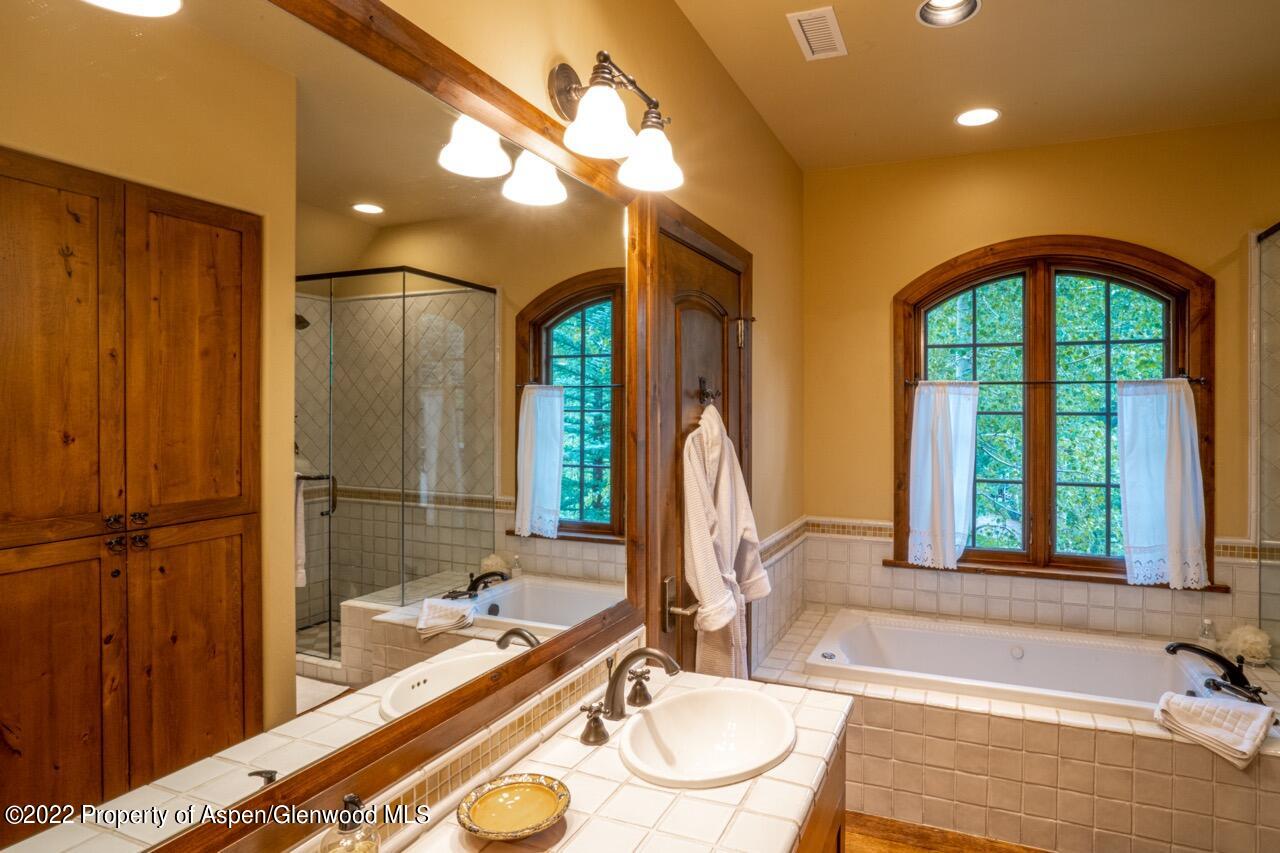 800 South Hayden Road Aspen, CO 81611 - Photo 48 of 60 a bathroom with a tub a sink and a large mirror