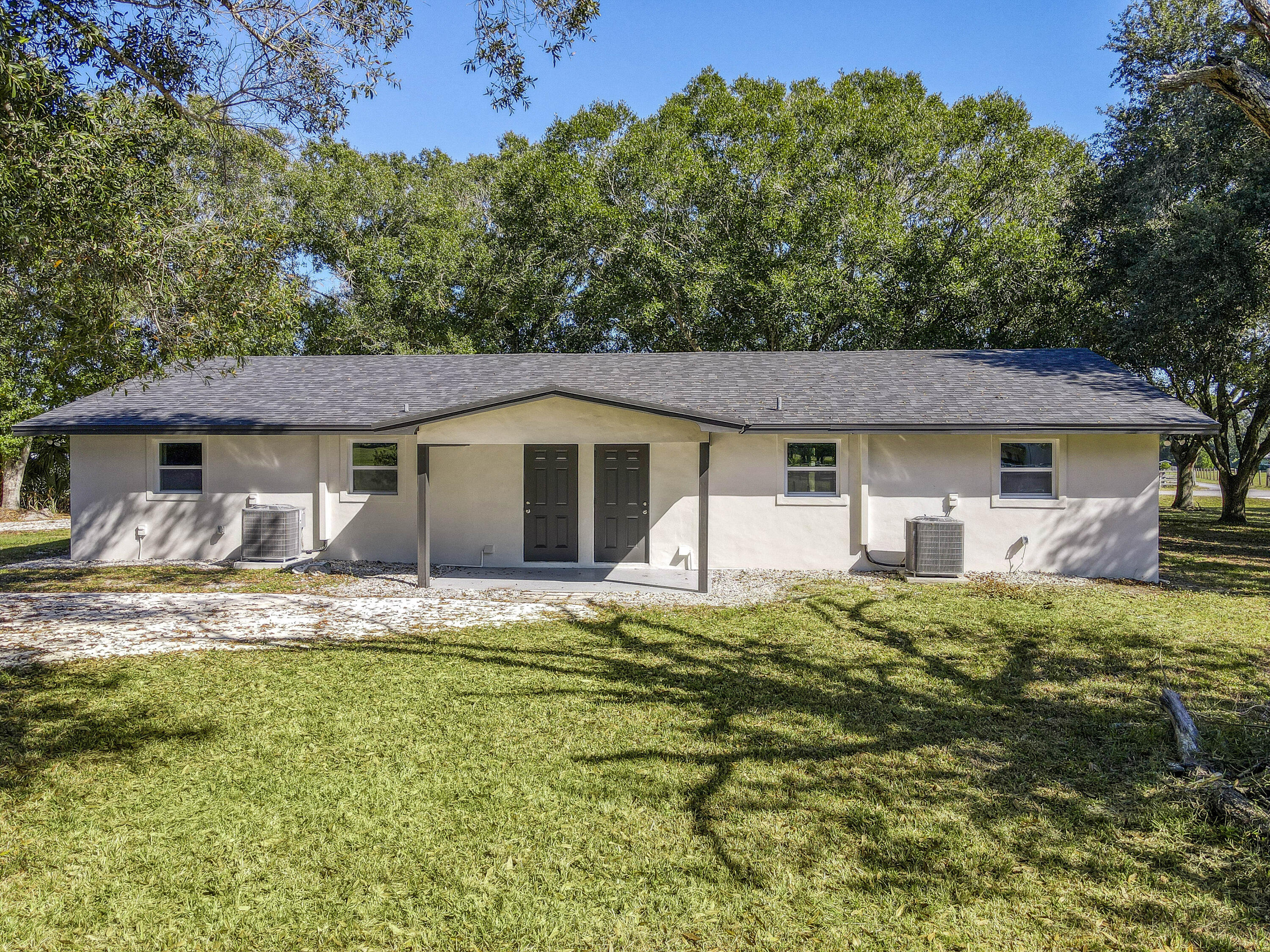 311 Southwest 67th Drive Okeechobee, FL 34974 - Photo 2 of 30 a white house covered with tall trees