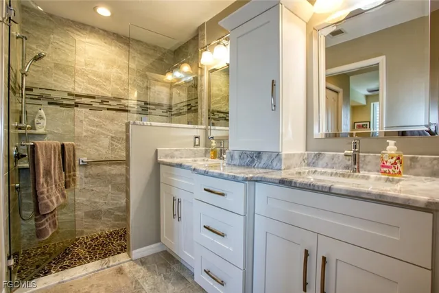 a bathroom with a granite countertop sink a mirror and shower
