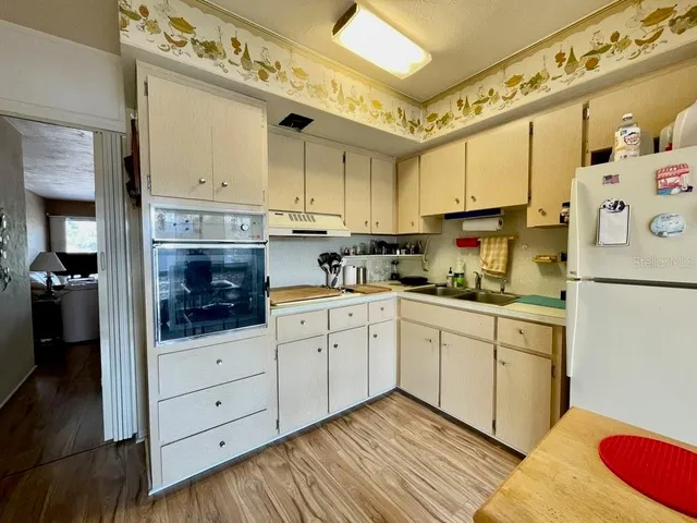 a kitchen with stainless steel appliances a sink cabinets and wooden floor