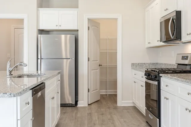 a kitchen with stainless steel appliances granite countertop a refrigerator a stove and a sink with wooden floor