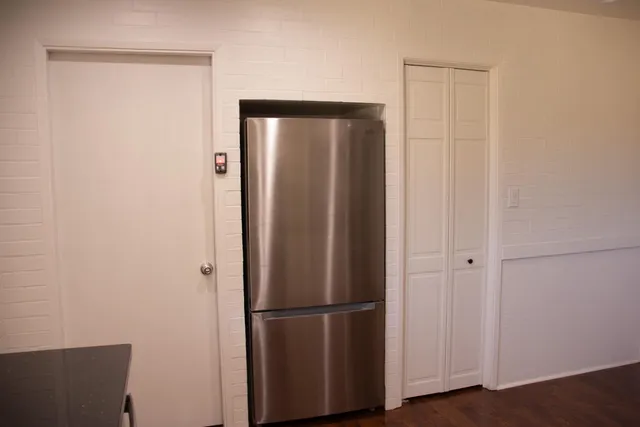 a view of a refrigerator in kitchen and white wooden cabinets