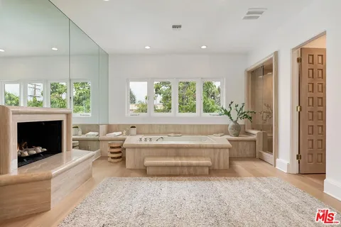 a large white kitchen with a fireplace and a large window