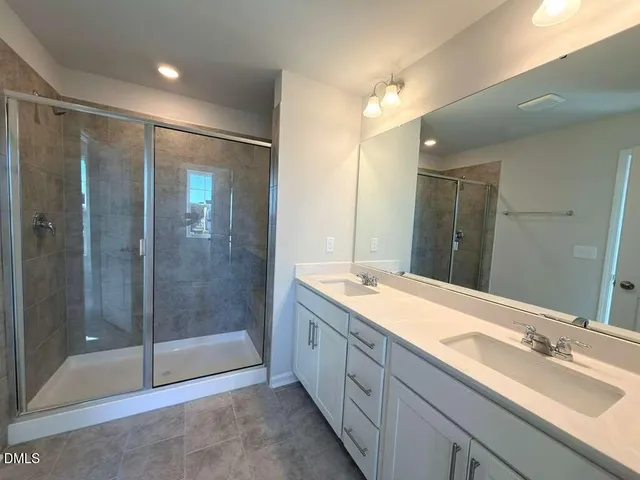 a spacious bathroom with a shower sink and mirror