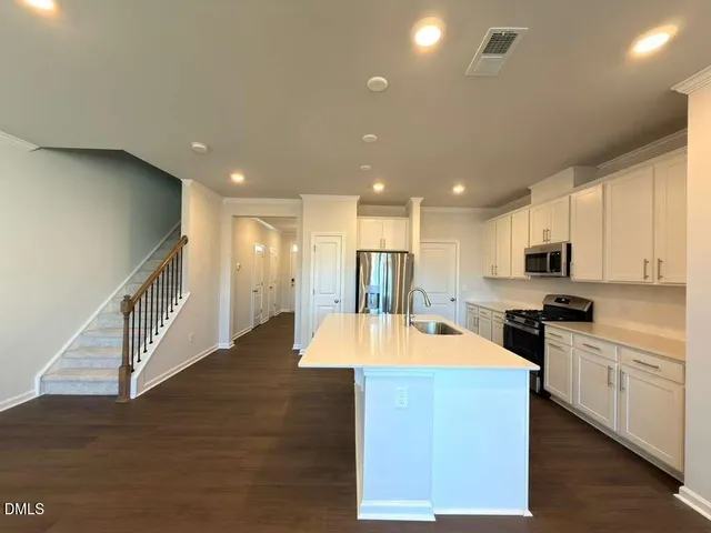 a large kitchen with stainless steel appliances kitchen island granite countertop a stove and a sink