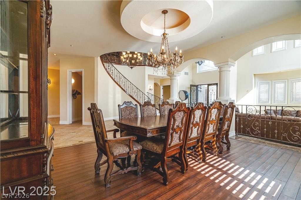 861 Majestic Ridge Court Henderson, NV 89052 - Photo 11 of 68 Dining area with decorative columns, arched walkways, dark wood-style floors, a raised ceiling, and hanging lights