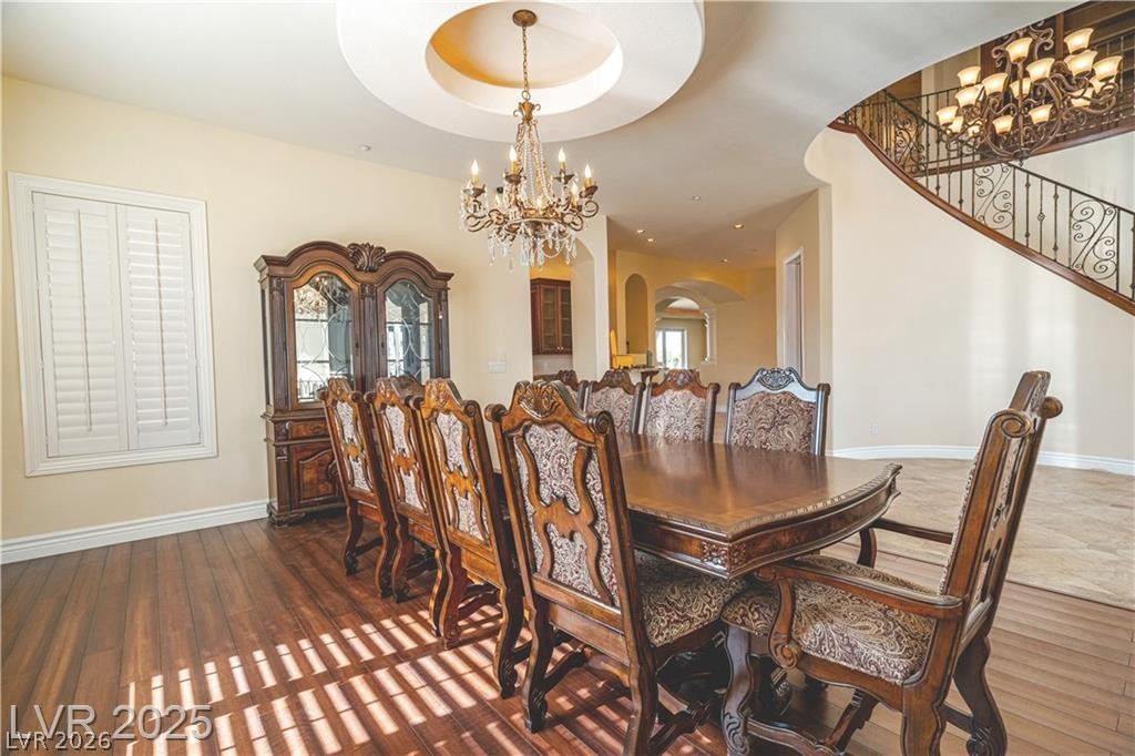 861 Majestic Ridge Court Henderson, NV 89052 - Photo 13 of 68 Dining area featuring suspended lighting, arched walkways, a raised ceiling, and dark wood-style floors