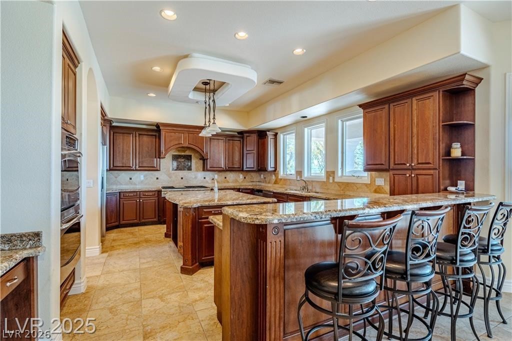861 Majestic Ridge Court Henderson, NV 89052 - Photo 20 of 68 Kitchen with a kitchen bar, open shelves, light stone countertops, and a kitchen island with sink