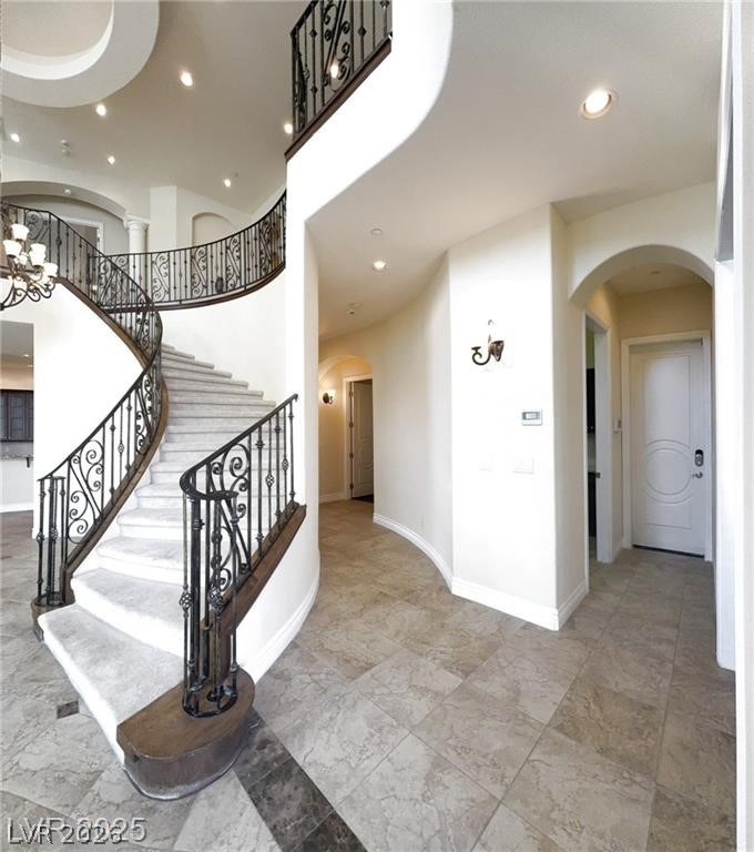 861 Majestic Ridge Court Henderson, NV 89052 - Photo 24 of 68 Staircase with arched walkways, a high ceiling, and hanging lights