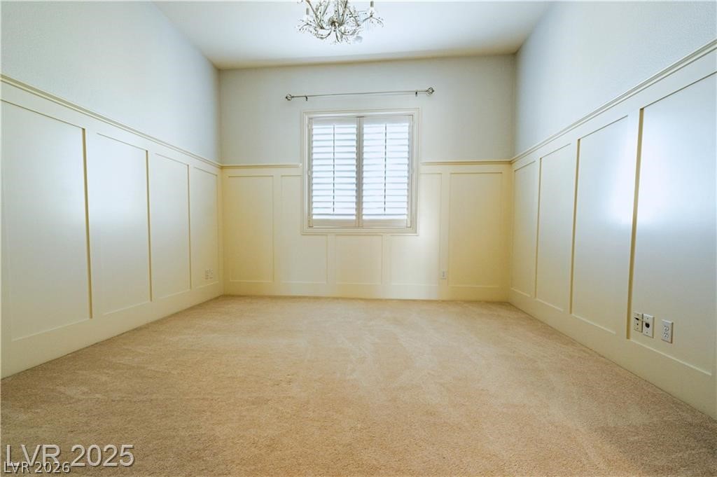 861 Majestic Ridge Court Henderson, NV 89052 - Photo 45 of 68 Spare room featuring a decorative wall, light carpet, a wainscoted wall, and a chandelier