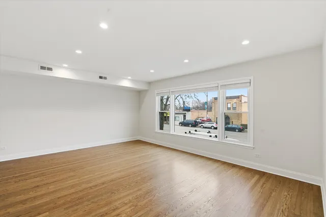 an empty room with wooden floor and large window