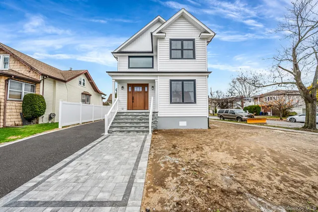 a front view of a house with cars parked on road