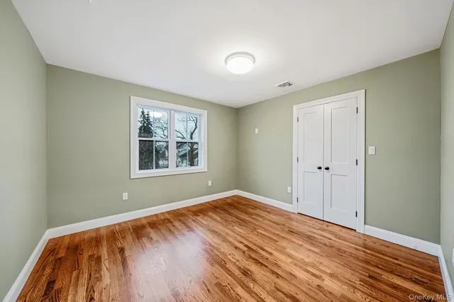 a view of an empty room with window and wooden floor