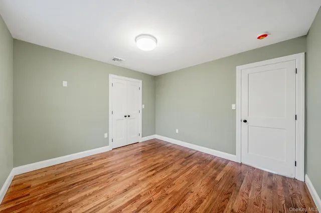 a view of empty room with window and wooden floor