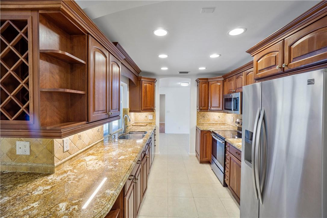 1423 Southwest 14th Street Boca Raton, FL 33486 - Photo 11 of 45 a kitchen with stainless steel appliances granite countertop a refrigerator a stove and a sink with granite countertops
