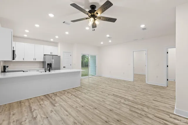 a view of an empty room with a chandelier fan and a window