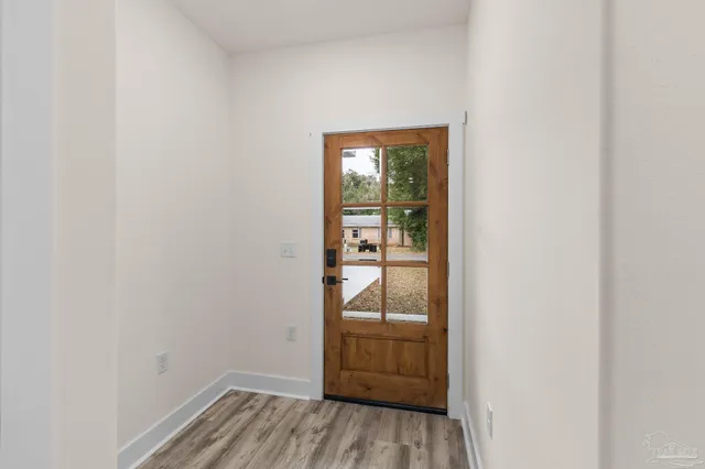 a view of a hallway with wooden floor and a bathroom