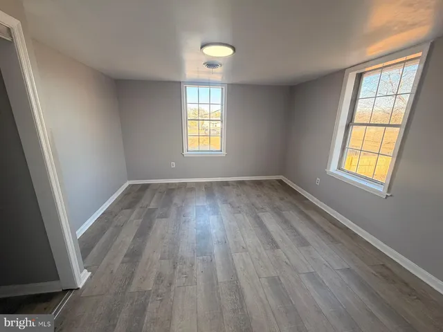 a view of empty room with window and wooden floor