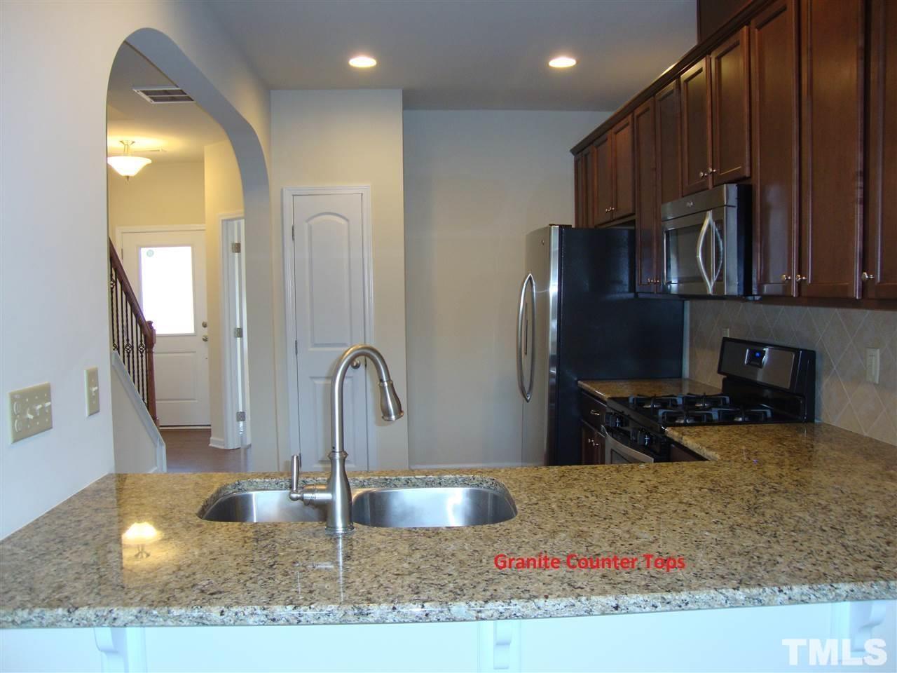 85 Intuition Circle Durham, NC 27705 - Photo 3 of 17 a kitchen with kitchen island granite countertop a sink and a stove top oven with wooden floor