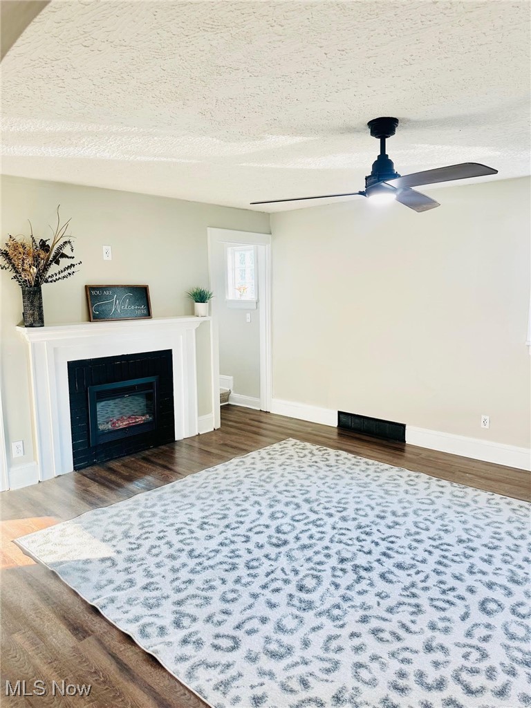 1389 Diagonal Road Akron, OH 44320 - Photo 10 of 20 Living area featuring baseboards, dark wood-style flooring, a ceiling fan, and a textured ceiling